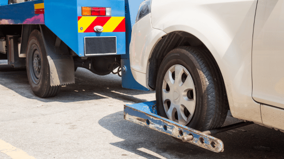 Tow truck towing a broken down car on the street